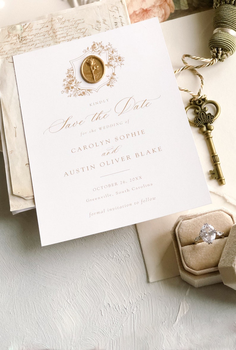 K&ouml;nnte beinhalten: Save the Date Hochzeitskarte mit einem goldenen Siegel aus Wachs und floralem Design. Die Einladung ist f&uuml;r Carolyn Sophie und Austin Oliver Blake, die Hochzeit findet am 26. Oktober 20XX in Greenville, South Carolina statt.
