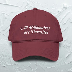 May include: A maroon baseball cap featuring the white embroidered text "All Billionaires are Parasites" in a cursive font across the front panel. The cap has a structured crown, a curved brim with stitching, and a button at the top center.