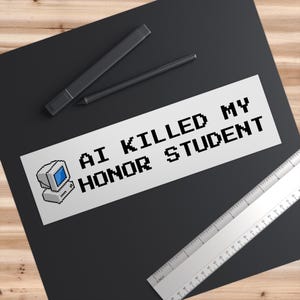 Può includere: Un adesivo bianco con la scritta "AI KILLED MY HONOR STUDENT" in carattere nero pixelato, accompagnato da una grafica di computer pixelata. L'adesivo è su una superficie nera, con un righello e due penne nere nelle vicinanze.