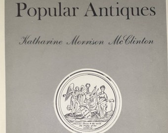 May include: A gray book cover with the title "A Handbook of Popular Antiques" by Katharine Morrison McClinton. The cover features a black and white illustration of a seal with a woman, a man, and an angel.
