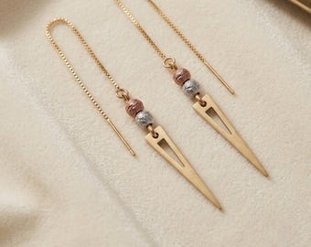 May include: A pair of gold-tone threader earrings featuring a delicate box chain. Each earring is accented with one textured rose gold-tone bead and one textured silver-tone bead, terminating in a long, slender, triangular gold-tone pendant.