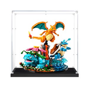 May include: A brick-built display featuring Charizard, Venusaur, and Blastoise figures inside a clear acrylic case. Charizard is positioned above, while Venusaur and Blastoise stand on a base with rocky, floral, and water-like elements.