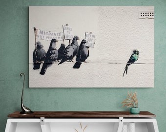 May include: A street art print featuring a group of pigeons holding signs with messages about immigration. The signs read "Migrants Not Welcome", "Go Back To Africa", and "Keep Me Our Homes". A single bird, possibly a swallow, is perched on a wire above the pigeons.