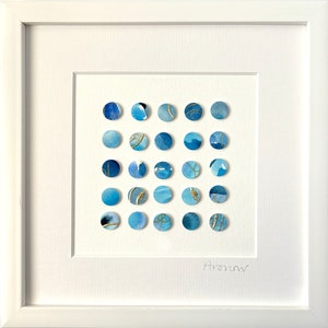 May include: A framed artwork featuring a grid of 36 blue and gold circles. The circles are arranged in a square pattern and have a watercolor effect. The artwork is signed "Anowar" in the bottom right corner.