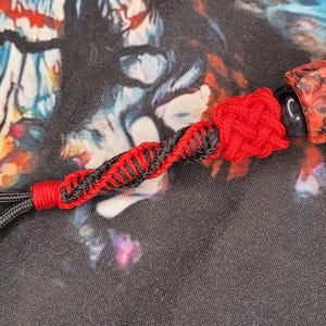 May include: A red and black paracord keychain with a red and black resin bead. The bead has a marbled pattern.