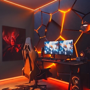 Puede incluir: Una moderna configuración de juego con un escritorio negro, dos monitores y una silla de juego. La habitación cuenta con iluminación LED naranja, una impresión artística de Batman y una alfombra estampada. Las paredes tienen un diseño geométrico.