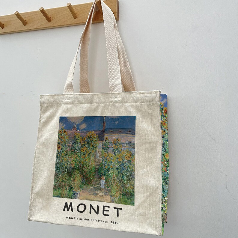 May include: A white canvas tote bag with a printed image of Claude Monet's "Monet's garden at V&eacute;theuil, 1880" painting. The painting depicts a garden with sunflowers and a small figure walking on a path.