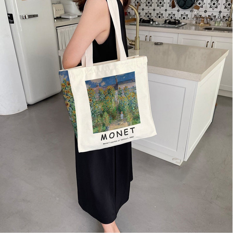 May include: A white canvas tote bag with a painting of a field of sunflowers by Claude Monet. The bag has the artist's name and the title of the painting, "Monet's garden at Vetheuil, 1880", printed on the bottom.