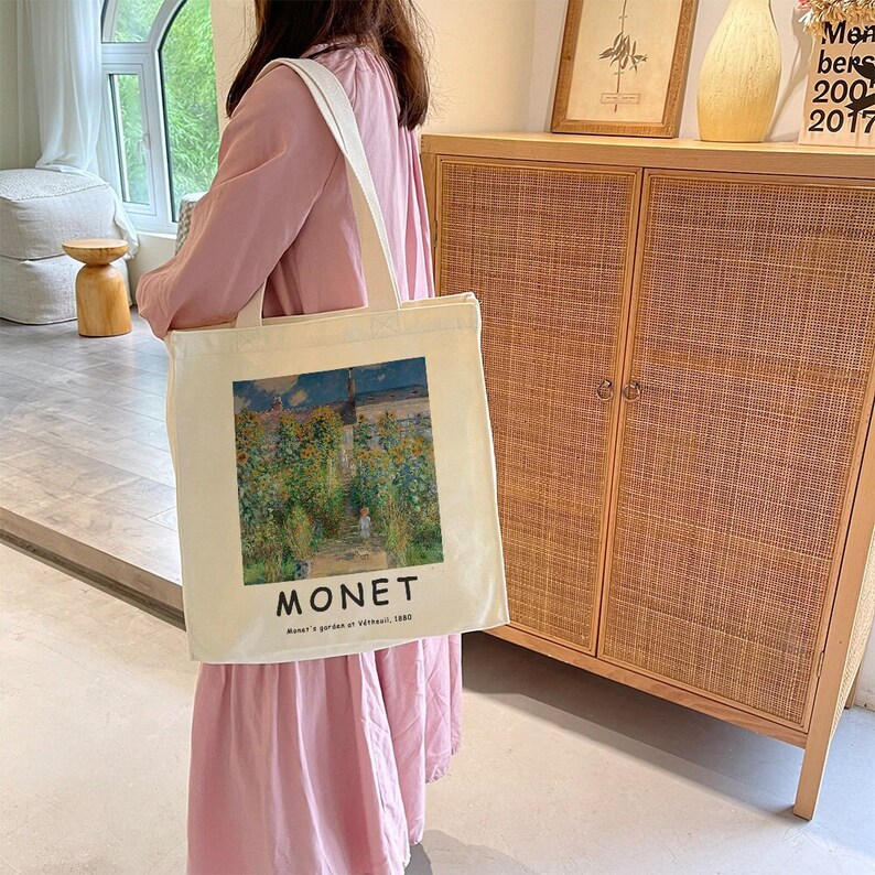 May include: A white canvas tote bag with a painting of a garden by Claude Monet. The bag has the words "MONET" and "Monet's garden at V&eacute;theuil, 1880" printed on it.