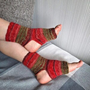 May include: Red and green striped knitted socks with open toes. The socks are made of a soft, comfortable material and are perfect for wearing around the house.