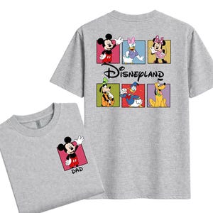 May include: Two gray t-shirts. One shirt has a small Mickey Mouse graphic with the word "DAD" on the front. The other shirt has a Disneyland graphic on the back with Mickey, Daisy, Minnie, Goofy, Donald, and Pluto.