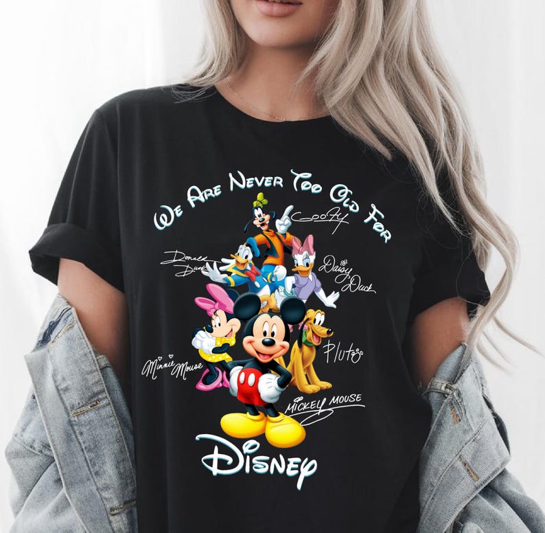 May include: Black t-shirt featuring a colorful graphic of Disney characters including Mickey Mouse, Minnie Mouse, Donald Duck, Daisy Duck, Goofy, and Pluto. The text "We Are Never Too Old For Disney" is printed above the characters, with the Disney logo below.