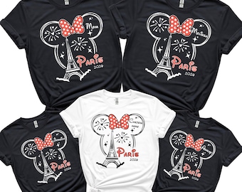 May include: Five t-shirts, four black and one white, featuring a Minnie Mouse-inspired design with a red bow, fireworks, and the Eiffel Tower. The word "Paris" and the year "2024" or "2026" are also printed on the shirts. Some shirts have custom names.