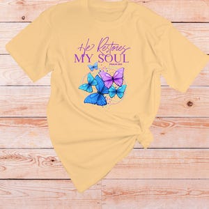 May include: A yellow t-shirt with a graphic of butterflies and the text "He Restores My Soul Psalm 23:3".
