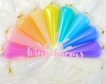 Könnte beinhalten: Eine Regenbogen-Auswahl von zehn durchsichtigen Plastikkegeln, gefüllt mit buntem Schleim. Die Kegel sind in einem Halbkreis angeordnet, mit dem Text "Wingcharms" in rosa Buchstaben in der Mitte.