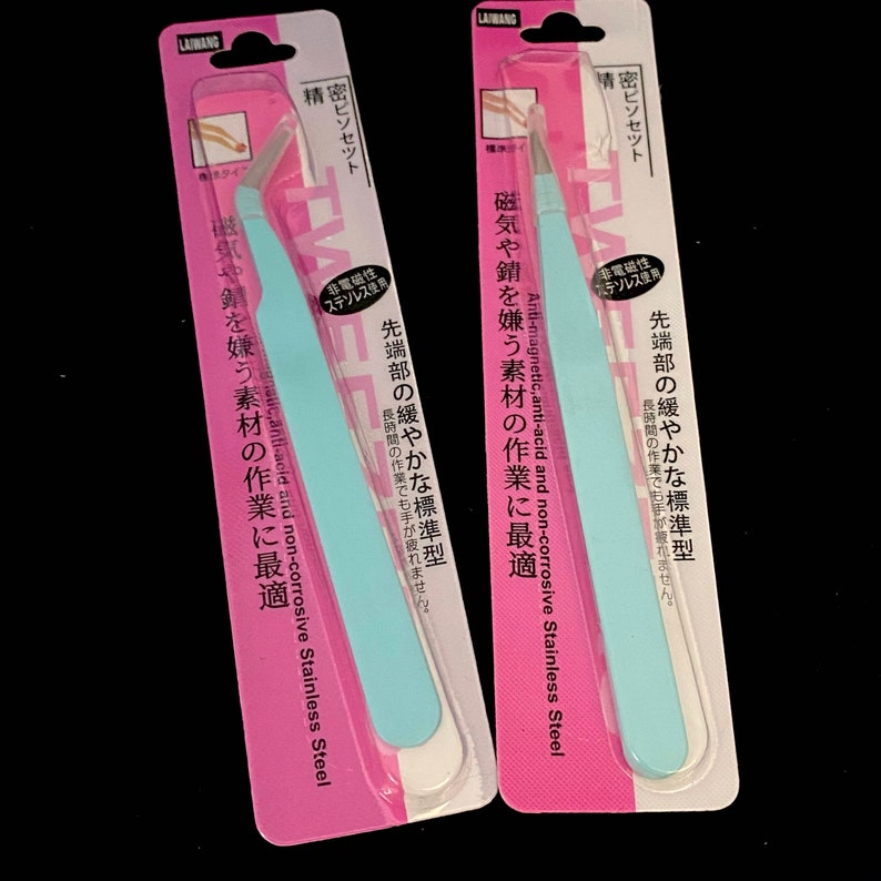 Puede incluir: Dos pares de pinzas de acero inoxidable azules con un embalaje rosa. El embalaje tiene texto japon&eacute;s que dice "Acero inoxidable antimagn&eacute;tico, anti&aacute;cido y no corrosivo" y "Para trabajos que requieren materiales sensibles al magnetismo, los &aacute;cidos y la corrosi&oacute;n."