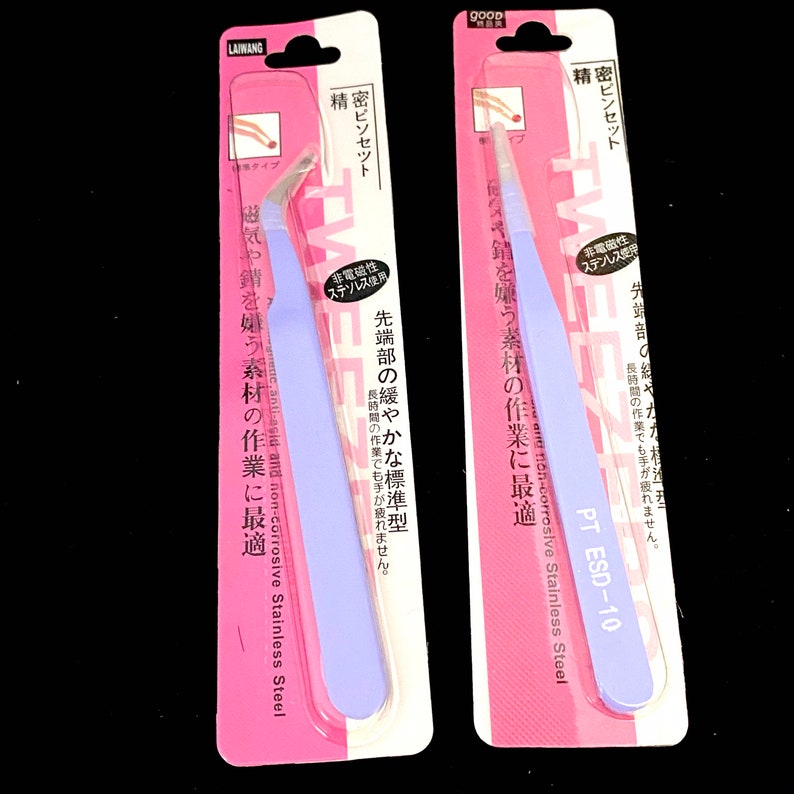 Puede incluir: Dos pares de pinzas con embalaje rosa. Las pinzas est&aacute;n etiquetadas con "精密ピンセット", que se traduce como "pinzas de precisi&oacute;n" en ingl&eacute;s. El embalaje tambi&eacute;n incluye el texto "非電磁性", que se traduce como "no magn&eacute;tico" en ingl&eacute;s. Las pinzas est&aacute;n hechas de acero inoxidable y est&aacute;n dise&ntilde;adas para trabajos de precisi&oacute;n.