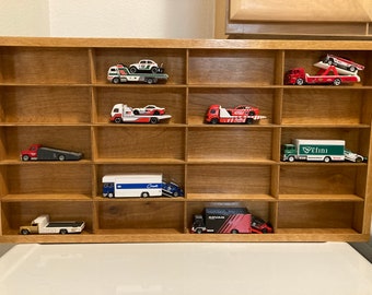 Puede incluir: Una vitrina de madera con 10 estantes, cada uno con un coche de juguete diferente. Los coches son principalmente rojos y blancos, con algunos detalles en negro y verde. La vitrina está hecha de madera marrón claro y tiene un diseño sencillo.