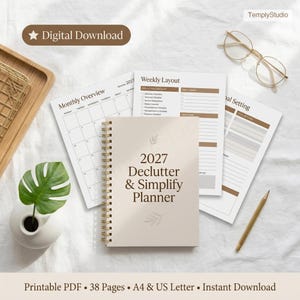 May include: A beige 2027 Declutter & Simplify Planner with a spiral binding, alongside planning pages and a calendar. The words "Digital Download" are at the top. The planner includes a weekly layout and goal setting pages. A pencil and glasses are also visible.