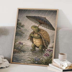 Op de afbeelding: Een ingelijste kunstprint toont een schildpad die zich onder een paraplu tegen de regen beschermt. De schildpad is groen en bruin, met een stro-achtige cape. De paraplu is zwart en beige. De achtergrond toont een landschap met bloemen en bomen.