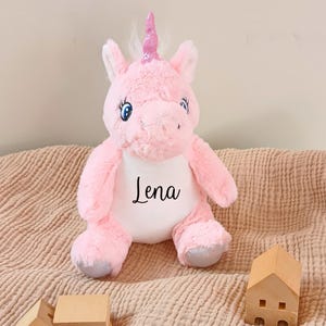 May include: Pink plush unicorn toy with a white embroidered patch that says "Lena".