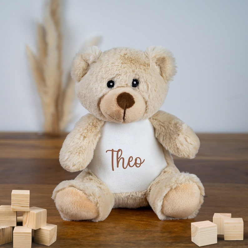 Personalisiertes Kuscheltier Teddy mit weichem Plüschfell, ideal als individuelles Geschenk für Kinder. Der Teddy ist mit einem Namen bedruckt und bietet einen treuen Kuschelfreund für kleine Abenteurer.