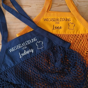 May include: Two blue and yellow reusable mesh shopping bags with white text that reads "Wechselkleidung von Ludwig" and "Wechselkleidung von Lene".