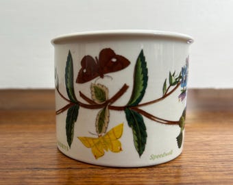 May include: White ceramic mug with a floral design featuring butterflies, leaves, and flowers. The mug has the text "Speedwell" on the bottom.