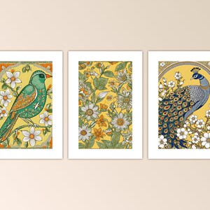May include: Three framed prints with a yellow background and floral designs. The left print features a green bird with a yellow beak and white flowers. The center print features white and yellow flowers with green leaves. The right print features a blue peacock with a yellow beak and white flowers.