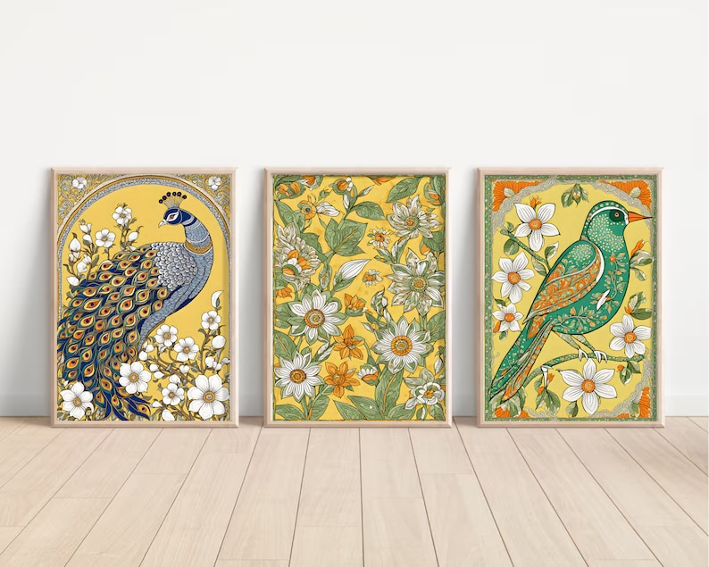 May include: Three framed prints with yellow backgrounds and floral designs. The left print features a blue and green peacock with white flowers. The center print features a floral design with green leaves and white flowers. The right print features a green bird with orange accents and white flowers.