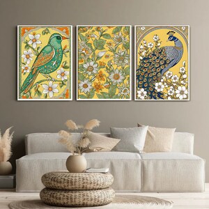 May include: Three framed canvas prints with floral patterns and birds. The left print features a green bird with yellow and white flowers. The center print features a yellow background with green leaves and white flowers. The right print features a blue peacock with white flowers and a yellow background.