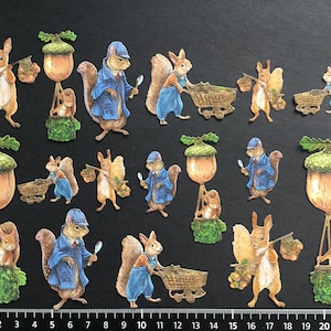 May include: A collection of 15 paper die-cut squirrel and acorn illustrations. The squirrels are wearing blue overalls and hats, and some are carrying baskets or wheelbarrows. The acorns are brown and have green leaves.