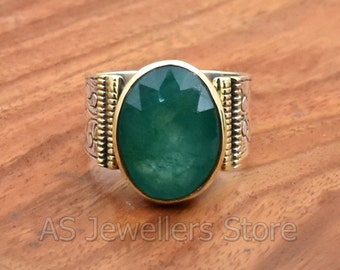 May include: A silver ring with a green oval gemstone set in a gold bezel. The ring band is decorated with a repeating pattern of small circles and dots.