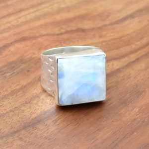 May include: A silver ring with a square-shaped moonstone. The ring has a textured band.