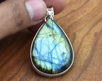 May include: A teardrop-shaped pendant with a silver setting and a blue and green labradorite gemstone.