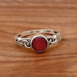 Op de afbeelding: Een zilveren ring met een rode robijn-edelsteen gezet in een Keltisch knoopontwerp.