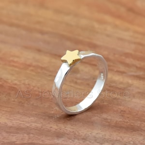 Puede incluir: Un anillo de plata con acabado martillado y una estrella dorada en la parte superior.