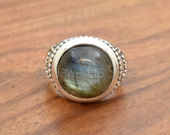 May include: A silver ring featuring a round, iridescent green and blue gemstone set in a beaded bezel.