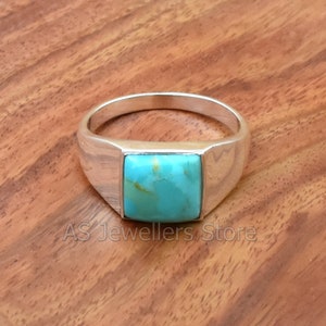 May include: A silver ring with a square turquoise stone set in a beveled band.