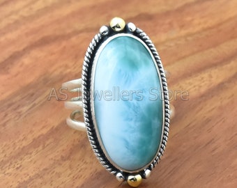 Könnte beinhalten: Ovaler Ring mit einem blauen und grünen Edelstein, der in einer silbernen Fassung mit goldenen Akzenten gefasst ist.