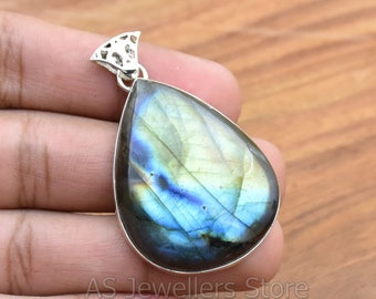 May include: A teardrop-shaped pendant with a silver bail and a large, iridescent labradorite gemstone. The gemstone has a blue, green, and gold color.