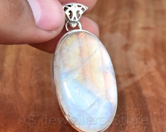 May include: Oval-shaped rainbow moonstone pendant with a silver bail. The stone has a white, blue, and yellow iridescent sheen.