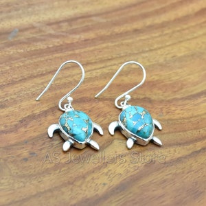 May include: A pair of silver turtle earrings with blue and gold turquoise stones.