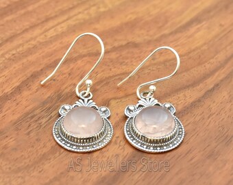 May include: A pair of silver earrings with a pink rose quartz stone in each. The earrings have a delicate, ornate design.