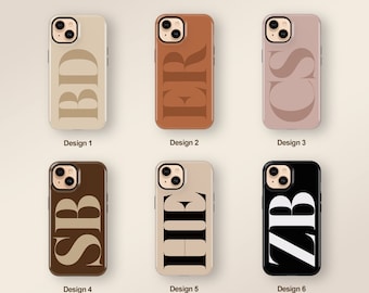 Puede incluir: Seis diseños diferentes de fundas para teléfono que presentan una sola letra en una fuente en negrita y estilizada. Las fundas son de varios colores, incluyendo beige, marrón, negro y rosa.