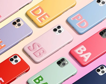 May include: A collection of colorful phone cases with different initials on them. The cases are all made of a soft, flexible material and have a matte finish. The initials are printed in a bold, white font.