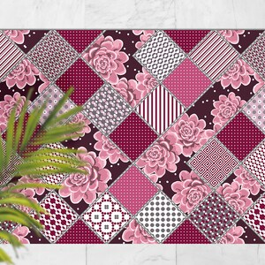 Puede incluir: Una alfombra de patchwork rosa y burdeos con un patrón floral. La alfombra está compuesta por diferentes cuadrados con varios patrones, incluyendo lunares, rayas y diseños geométricos.