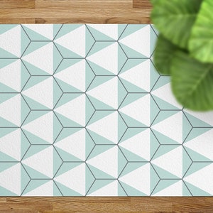 May include: A white and light blue geometric patterned rug with a hexagonal design. The rug has a subtle texture and is made of a soft material.