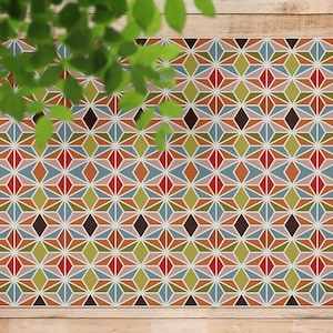 Può includere: Un tappeto con motivo geometrico con un designo ripetitivo di stelle multicolori. Il tappeto presenta sfumature di rosso, arancione, blu, verde e marrone.
