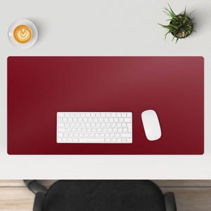 May include: A red leather desk mat with a white keyboard and a white mouse. The mat is on a white desk.